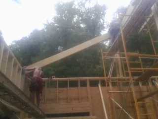 Carpenter raising a rafter beam on a new second story frame in Belton