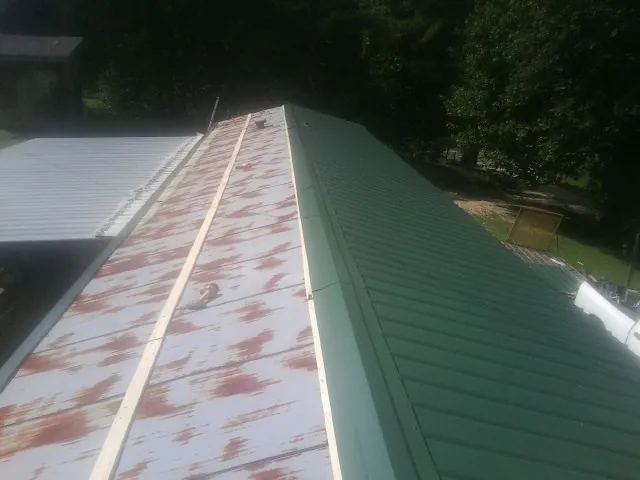 Old rusted panels beside newly installed green metal roofing — Wind Damage Roof Repair by Roofing Brothers in Belton